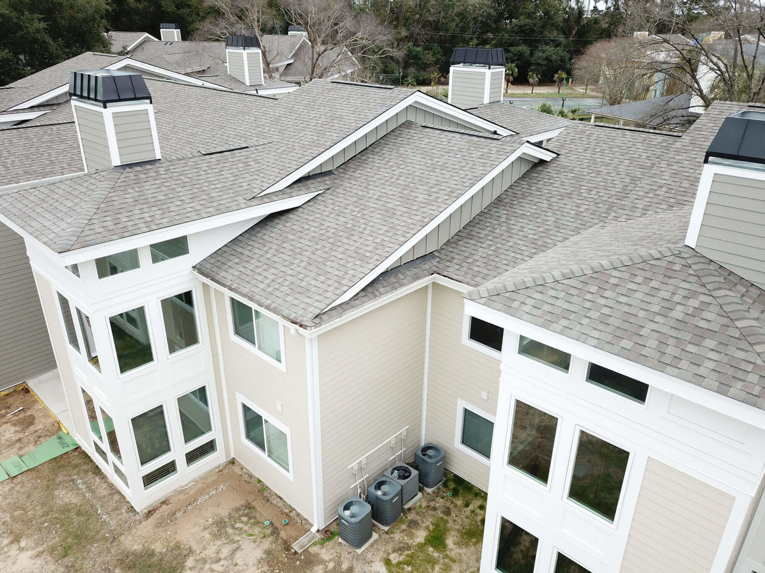 Large multi-unit residential property with white gutters and many windows.
