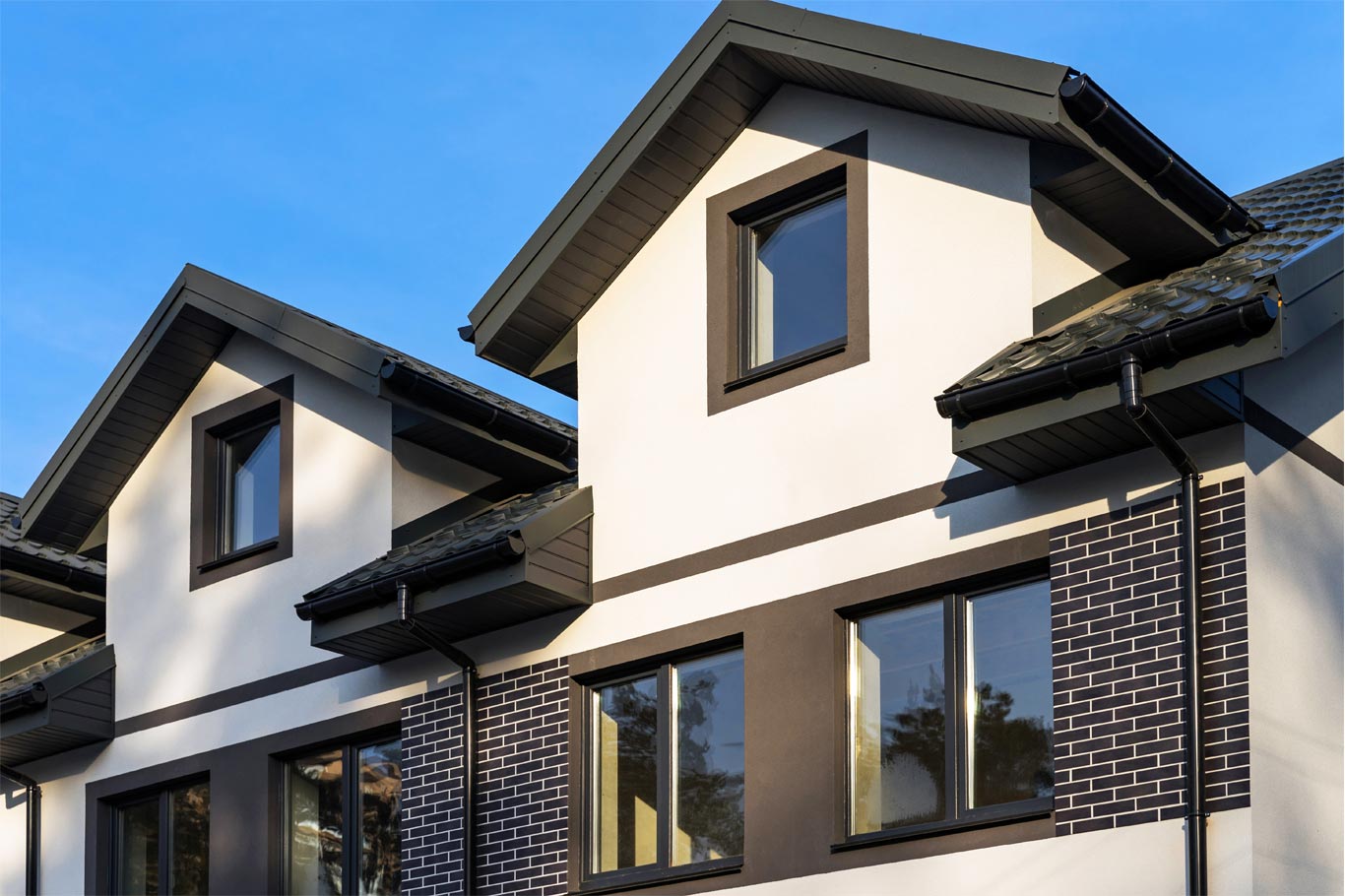 Modern tan and brown home with brown gutters and drains.