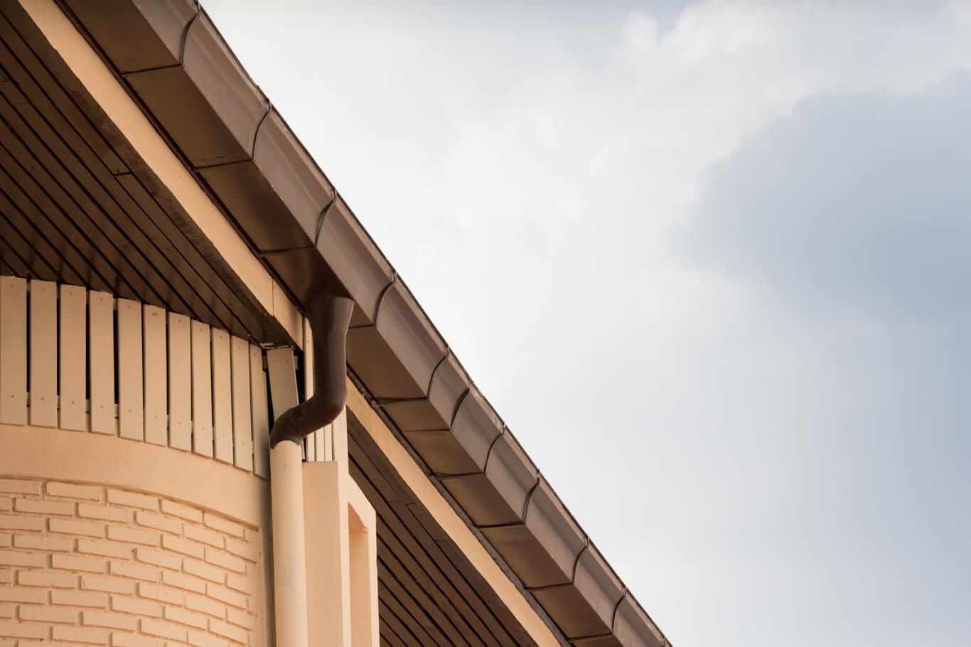 Close up of copper gutters with beige downspout.