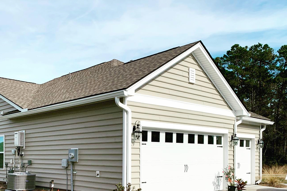Beige garage with white doors and white gutter system.